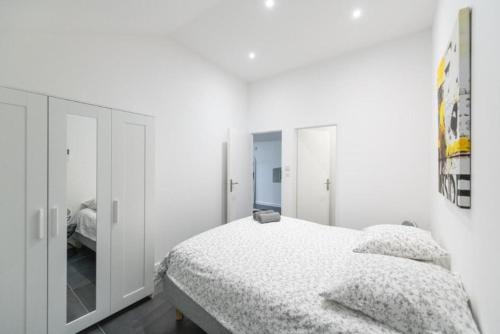 une chambre blanche avec un lit et un miroir dans l'établissement T3 spacieux avec terrasse et parking privatif, à Saint-Étienne
