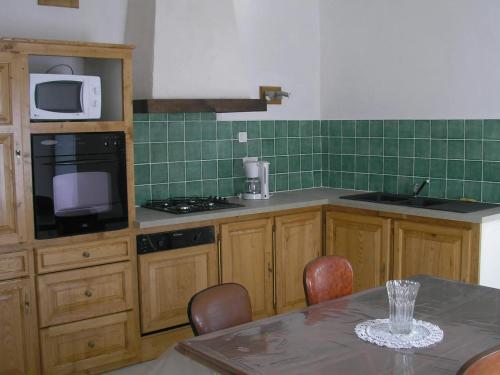 une cuisine avec des armoires en bois et une table avec des chaises dans l'établissement Maison accueillante à Saint-Martin-de-Boubaux, jardin agréable, à Saint-Martin-de-Boubaux