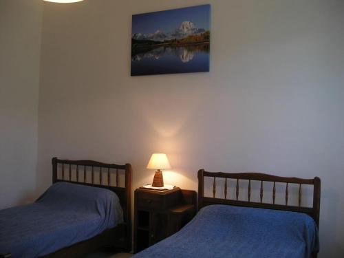Cette chambre comprend deux lits et une lampe sur une table. dans l'établissement Maison accueillante à Saint-Martin-de-Boubaux, jardin agréable, à Saint-Martin-de-Boubaux