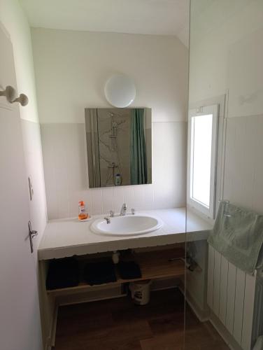 une salle de bain blanche avec un lavabo et un miroir dans l'établissement La Maisonnette, à Lugagnan