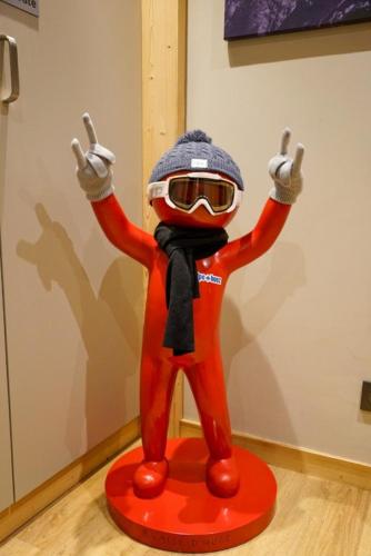 une statue d'une personne en costume rouge et lunettes de protection dans l'établissement HSH Huez Sweet Huez, à L'Alpe-d'Huez