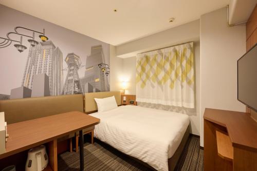 a room with a bed and a desk and a tv at Via Inn Shin Osaka in Osaka