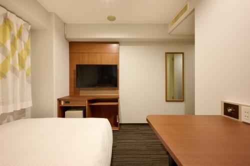 a hotel room with a bed and a desk at Via Inn Shin Osaka in Osaka
