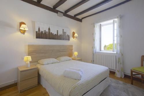 Un dormitorio con una gran cama blanca y una ventana. en Maison Beltzenia, en Urrugne