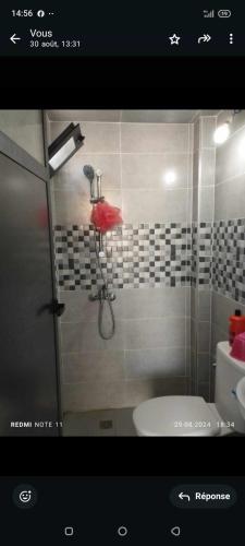 a bathroom with a shower with a red umbrella at Petit appartement in Meknès