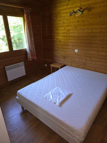 Cette chambre en bois dispose d'un lit blanc et d'une fenêtre. dans l'établissement CHALET 6 Personnes, à Uxelles