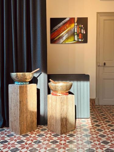 two bowls on wooden stands in a room with a painting at La Maison in Les Vans