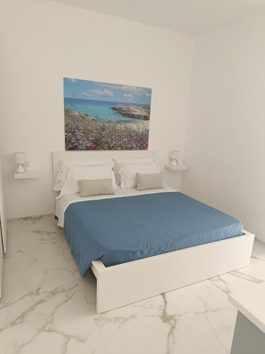 a white bedroom with a bed with a painting on the wall at La casa di mest Pepp in Monopoli