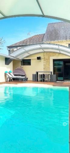 une piscine bleue devant une maison dans l'établissement La villa épicurienne, à Bellengreville