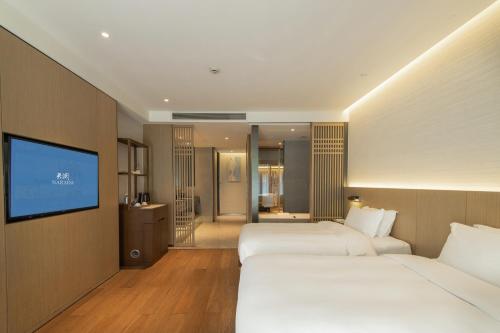 a hotel room with two beds and a flat screen tv at Dongqian Lake Junlan Resort Hotel in Ningbo