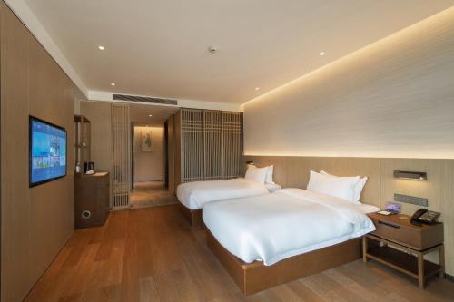 a hotel room with two beds and a flat screen tv at Dongqian Lake Junlan Resort Hotel in Ningbo