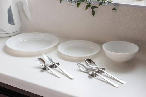 three white plates and silverware sitting on a counter at 小田原シーサイドハウス in Odawara