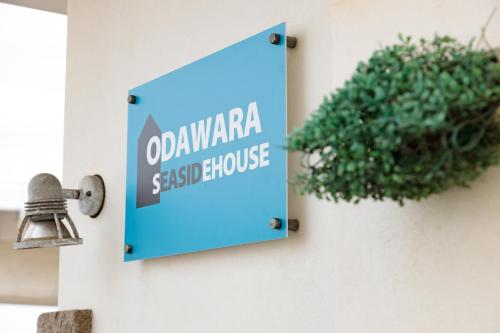 a sign on a wall with a potted plant at 小田原シーサイドハウス in Odawara