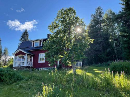 a red house with a tree in a field at Fritidshus in Grynberget