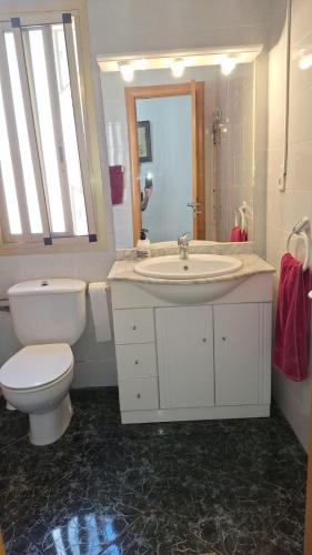 a white bathroom with a toilet and a sink at Apartamento con encanto in Torredembarra