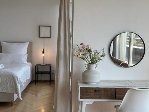 a bedroom with a bed and a vase with flowers on a table at Flow Living Penthouse in See- und Bahnhofsnähe in Herrsching am Ammersee