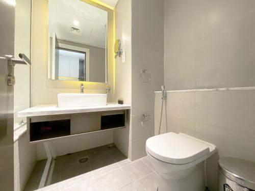 a bathroom with a toilet and a sink and a mirror at Vista Chic Studio in Prive By Damac-14 in Dubai