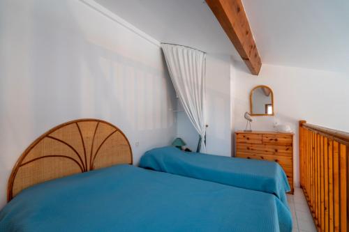 ein Schlafzimmer mit einem blauen Bett und einer Holzkommode in der Unterkunft Villa bord de mer in Gruissan