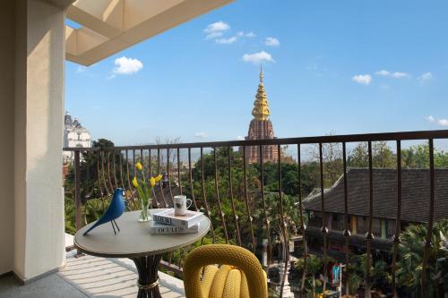 a balcony with a table and chairs and a view of a tower at voco Xishuangbanna Gaozhuang by IHG in Jinghong