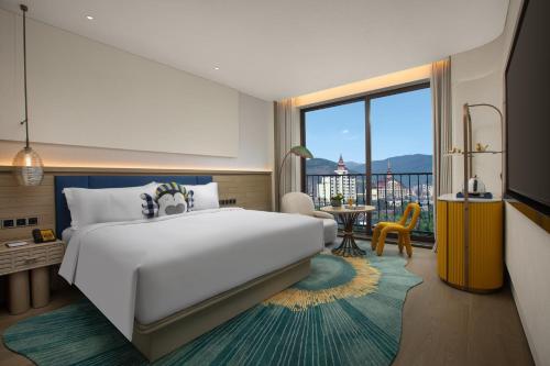a bedroom with a large white bed and a large window at voco Xishuangbanna Gaozhuang by IHG in Jinghong