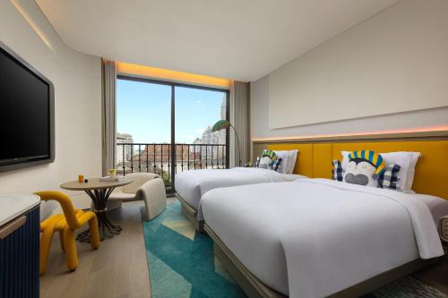 a hotel room with two beds and a television at voco Xishuangbanna Gaozhuang by IHG in Jinghong