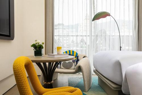a hotel room with a bed and a table and a chair at voco Xishuangbanna Gaozhuang by IHG in Jinghong