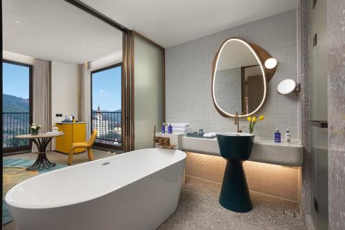 a bathroom with a tub and a large mirror at voco Xishuangbanna Gaozhuang by IHG in Jinghong