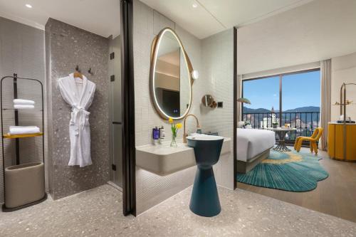 a bathroom with a sink and a toilet and a mirror at voco Xishuangbanna Gaozhuang by IHG in Jinghong