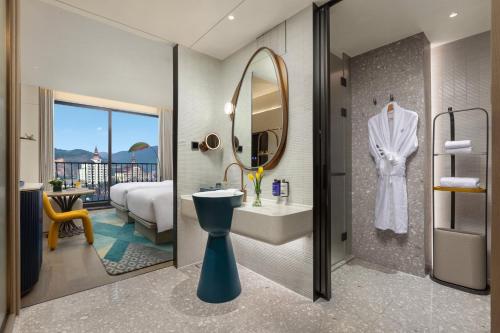 a bathroom with a sink and a mirror at voco Xishuangbanna Gaozhuang by IHG in Jinghong