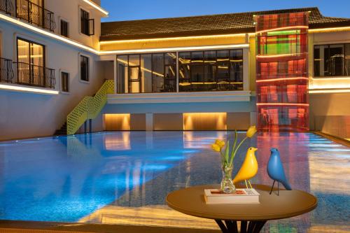 a large swimming pool with a table in front of a building at voco Xishuangbanna Gaozhuang by IHG in Jinghong