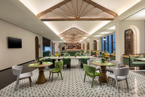 a restaurant with tables and chairs in a room at voco Xishuangbanna Gaozhuang by IHG in Jinghong