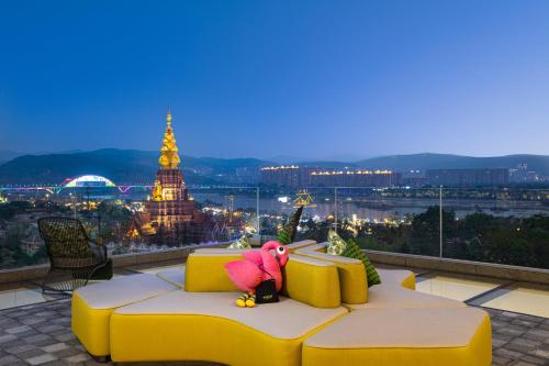 a pink stuffed animal sitting on a yellow couch on a building at voco Xishuangbanna Gaozhuang by IHG in Jinghong