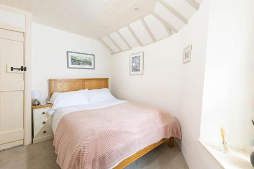 a white bedroom with a bed and a window at The Bakehouse in Port Isaac
