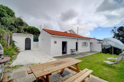 a backyard with a wooden picnic table and an umbrella at Murches' House in Alcabideche