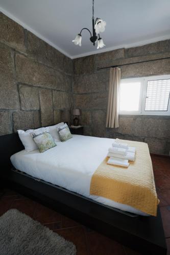 a bed in a room with a brick wall at Penedo Village in Marco de Canaveses