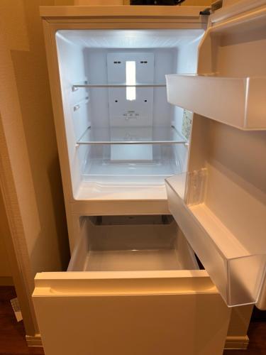 an empty refrigerator with its door open in a kitchen at The Noborisaka Village -登り坂ビレッジ- in Fujikawaguchiko
