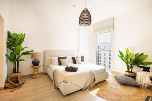 a white bedroom with a bed and a large window at Voyage's Two-bedroom Haven in Yas Island