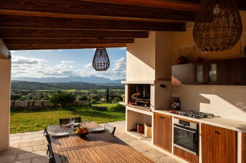 a patio with a table and a kitchen with a view at Sa Figuereta Living Place in Ariany
