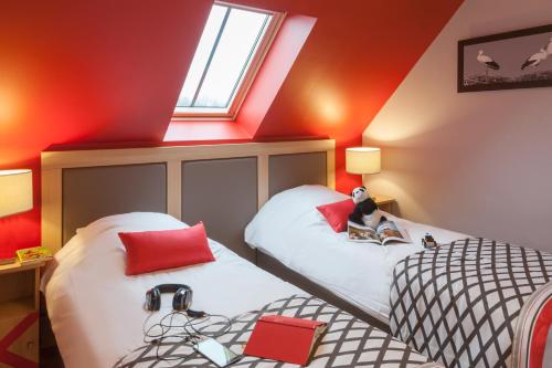 two beds in a room with red walls at Résidence Pierre & Vacances La Petite Venise in Colmar