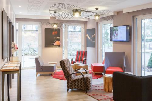 a waiting room with chairs and tables and windows at Résidence Pierre & Vacances La Petite Venise in Colmar