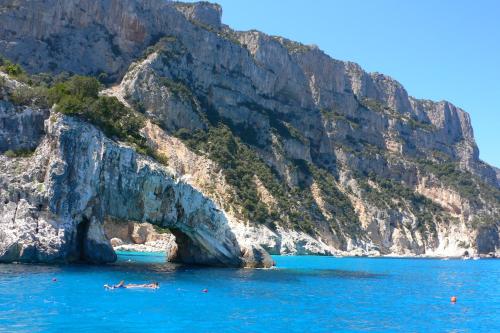 a boat in the water next to a mountain at Guest House - La bella vita in Orosei