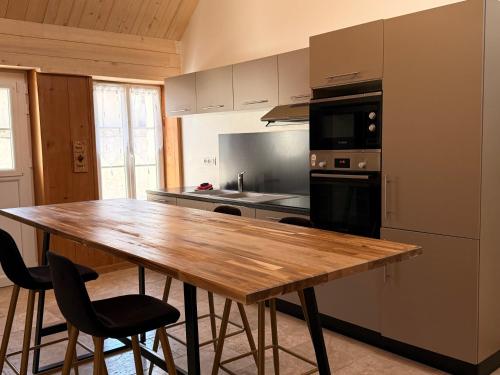 une cuisine avec une table en bois avec des chaises et un réfrigérateur dans l'établissement Thynoé - Châteaux - Loire à vélo, à Muides-sur-Loire