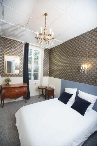 - une chambre avec un lit blanc et un lustre dans l'établissement Chateau de Mont-vert, à Saint-Zacharie
