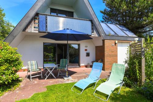 a group of chairs and an umbrella in front of a house at Ferienhaus Leevje in Neuharlingersiel
