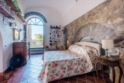 Un dormitorio con una cama y una pared de piedra. en Casa Valeria in the countryside, en SantʼAgata sui Due Golfi