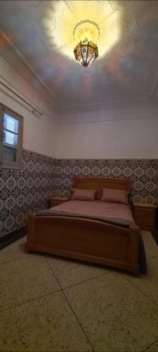 a bedroom with a bed with a chandelier on the ceiling at Maison Halimos in Midelt