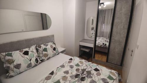 Un dormitorio pequeño con una cama y un espejo. en Hedonist Garden Luxury Apartments, en Doboj