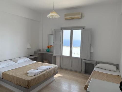 a white bedroom with two beds and a window at Hotel Hellas in Fira