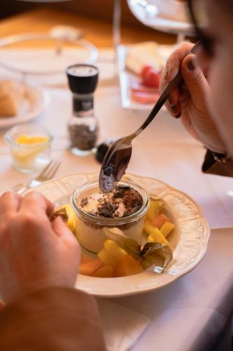 a person is eating food from a bowl on a plate at Pension Lahn in Rablà