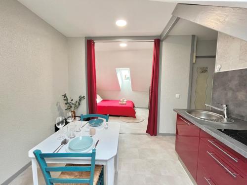 une cuisine avec une table, des chaises et un canapé rouge dans l'établissement Pause cosy - Châteauroux Centre, à Châteauroux